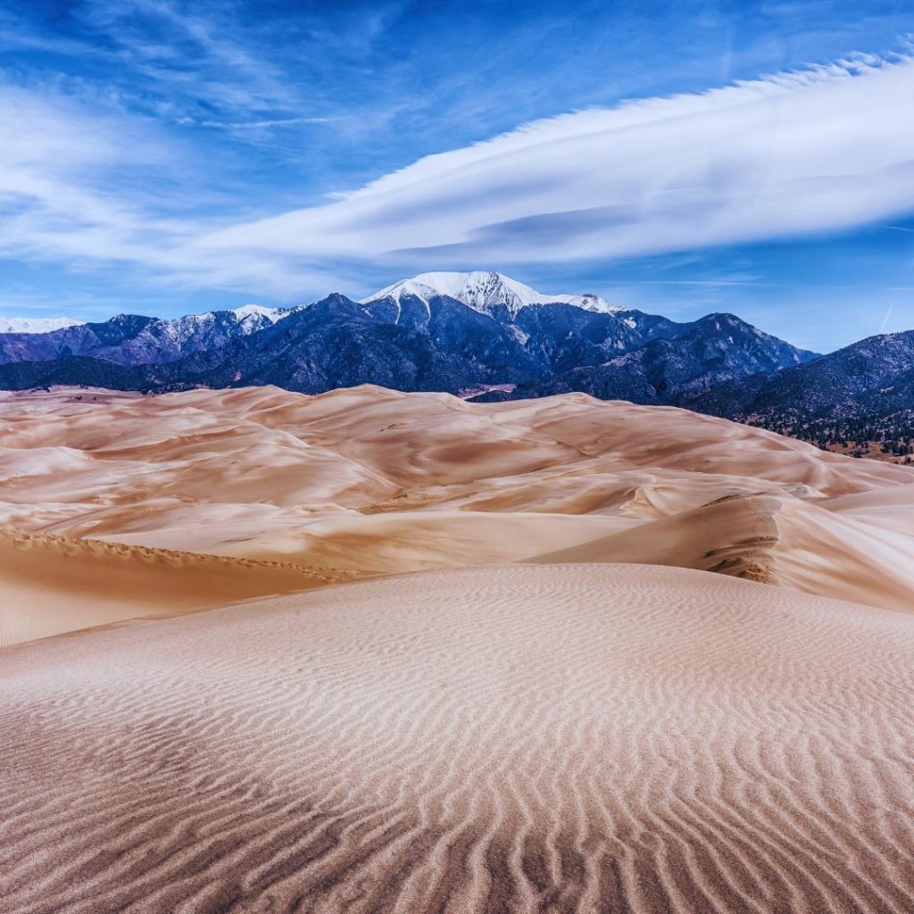 The great sand dunes national park with mountains in the background and a blue sky full of clouds